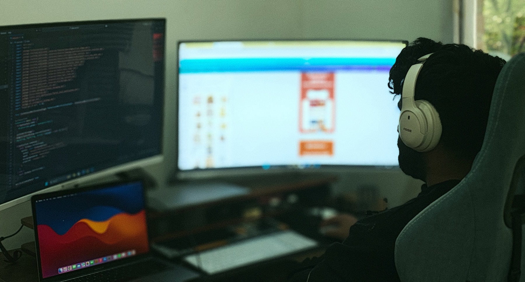Sviluppatore web al lavoro su più monitor